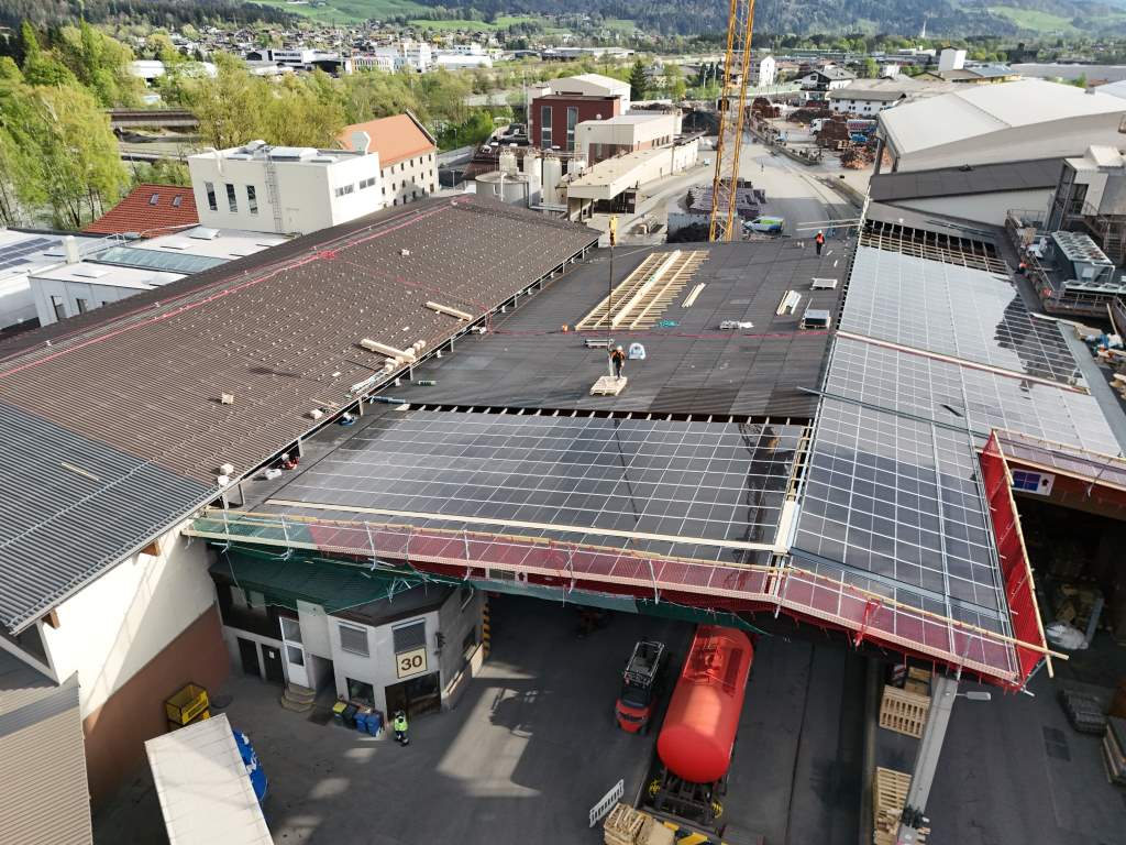 Drohnenaufnahme des Baufortschritts auf einem Industriegelände mit Installation von Solarpaneelen auf Dächern